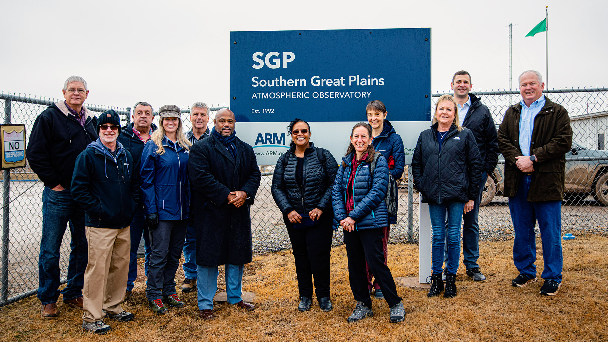 Group of visitors stands near sign for the Southern Great Plains atmospheric observatory