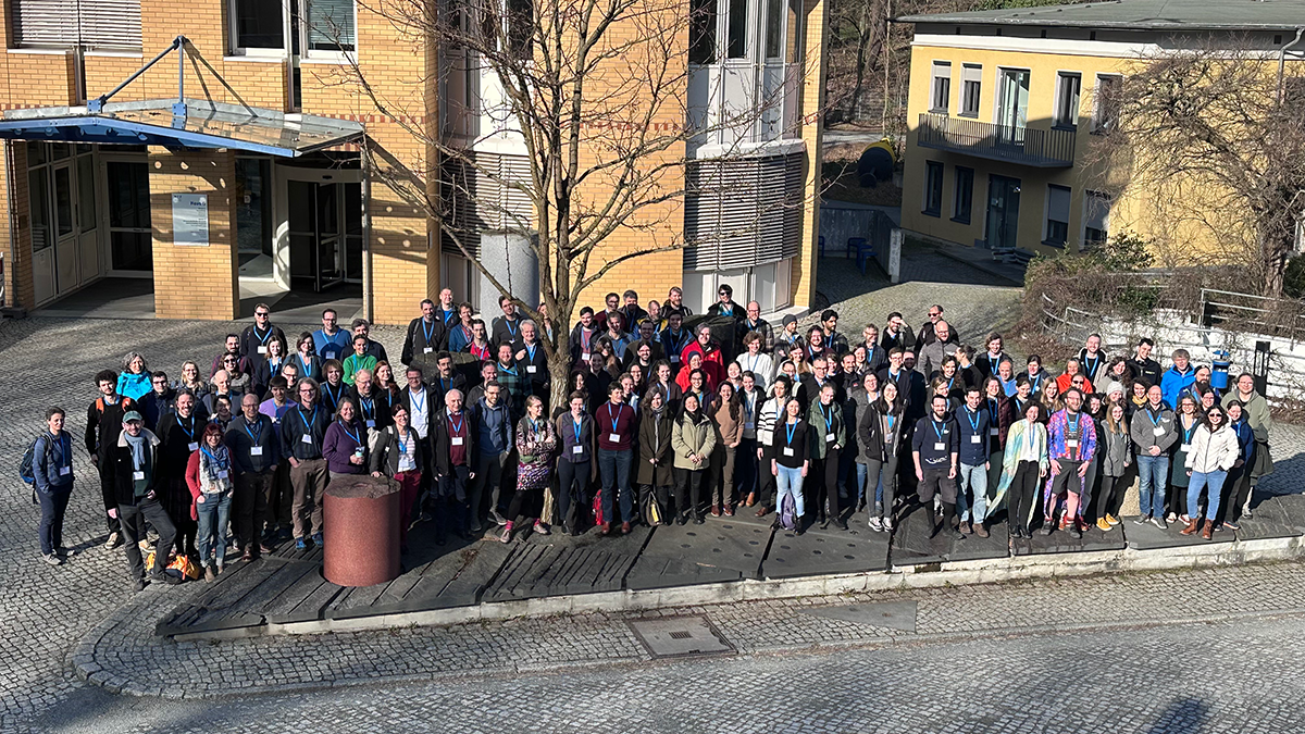 Attendees of the 3rd MOSAiC Science Conference (3MSC) stand together on a sidewalk in Potsdam, Germany, and look up at the camera for a group photo.